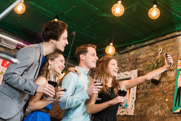 Glückliche Freunde, die selfie auf Mobiltelefon am Cocktailbarrestaurant nehmen