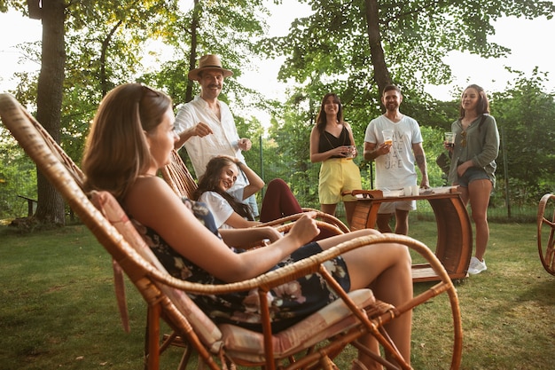 Kostenloses Foto glückliche freunde essen und trinken bier beim grillabendessen bei sonnenuntergang