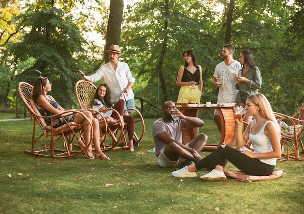 Kostenloses Foto glückliche freunde essen und trinken bier beim grillabendessen bei sonnenuntergang