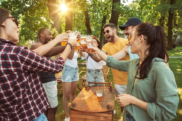 Glückliche Freunde haben Bier und Grillparty am sonnigen Tag