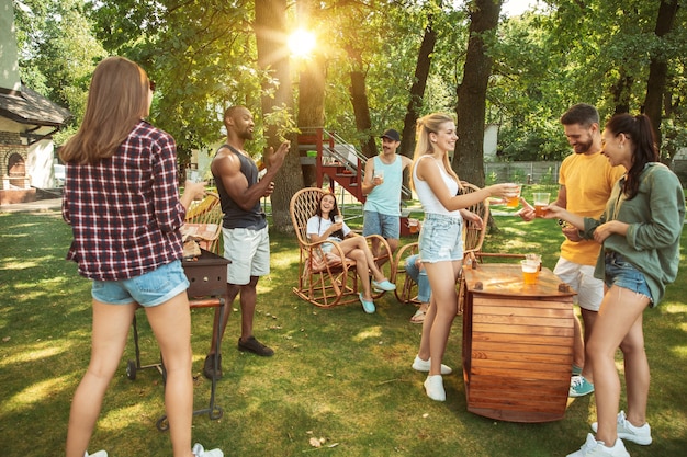 Glückliche Freunde haben Bier und Grillparty am sonnigen Tag