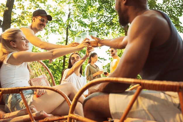 Glückliche Freunde haben Bier und Grillparty am sonnigen Tag