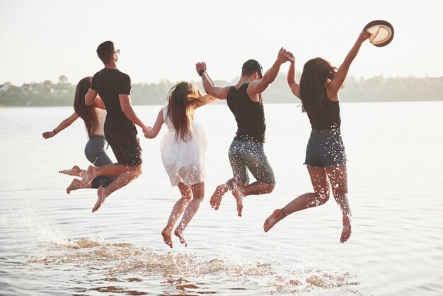 Glückliche Freunde haben Spaß am Strand - Junge Leute spielen in den Sommerferien im Freien.