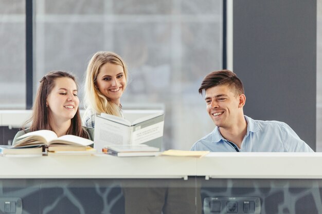 Glückliche Freunde in der Bibliothek mit Büchern