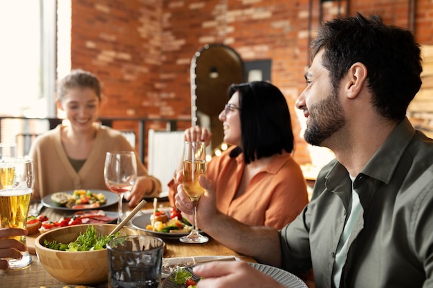 Glückliche Freunde sitzen am Tisch mittlerer Schuss