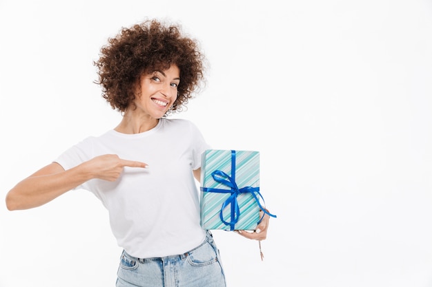 Glückliche fröhliche Frau, die Finger auf eine Geschenkbox zeigt