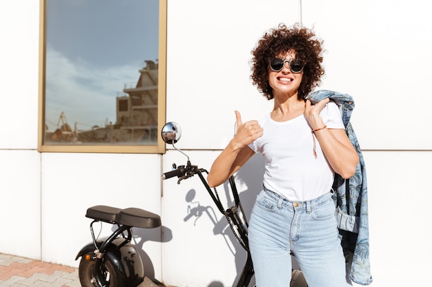 Glückliche fröhliche Frau in der Sonnenbrille, die aufwirft