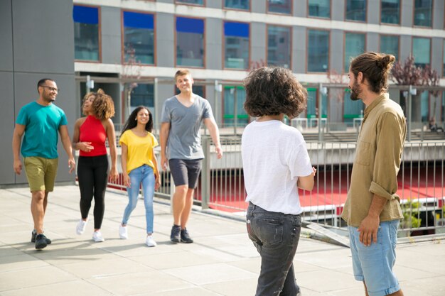 Glückliche frohe multiethnische Freunde, die sich draußen treffen