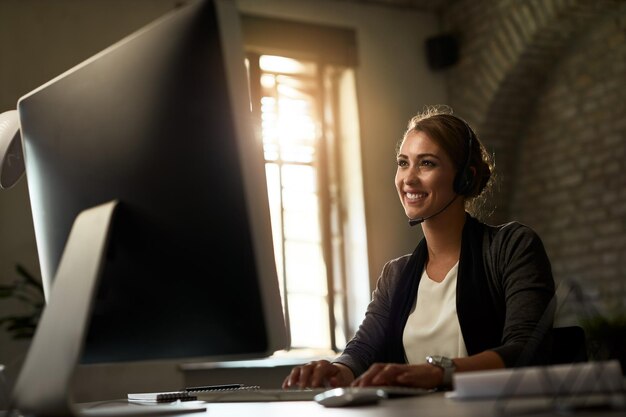 Glückliche Geschäftsfrau, die eine E-Mail auf dem Desktop-PC im Büro eingibt