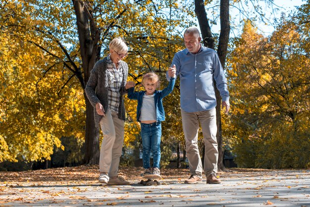 Glückliche Großeltern, die mit ihrem Enkel im Park spielen
