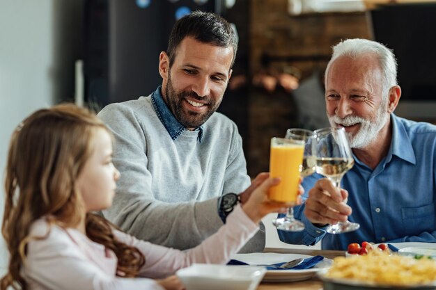 Glückliche Großfamilie, die Spaß beim Toasten während des Mittagessens am Esstisch hat Der Fokus liegt auf dem jungen Mann