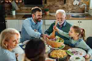 Kostenloses Foto glückliche großfamilie, die zu mittag isst und gesundes essen am esstisch isst