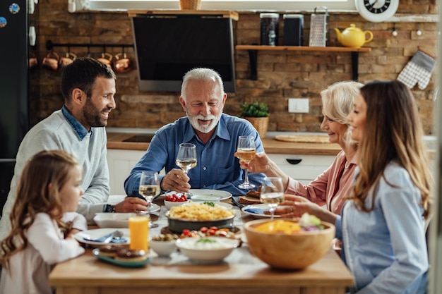 Glückliche Großfamilie, die zusammen im Speisesaal zu Mittag isst Der Fokus liegt auf dem älteren Mann