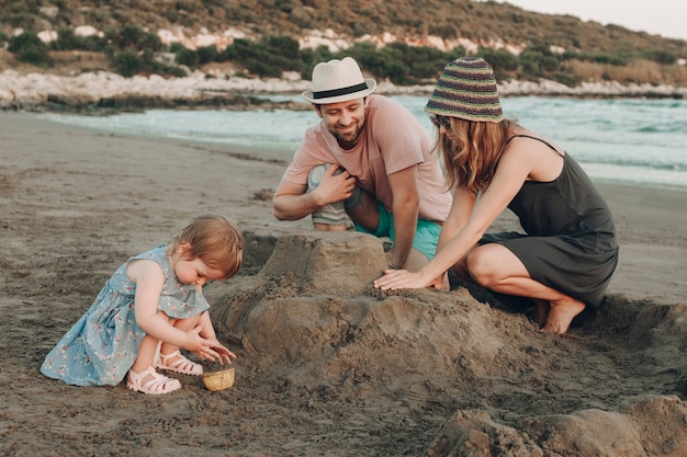 Glückliche hippie-familie am strandgebäudesandburg