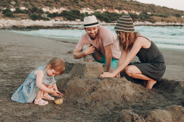 Glückliche Hippie-Familie am Strandgebäudesandburg