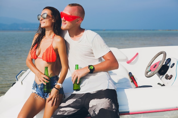 Glückliche Hipster-Frau und Mann, die Bier im tropischen Sommerurlaub in Thailand trinken, das auf Boot im Meer reist, Party am Strand, Leute, die Spaß zusammen haben, positive Emotionen