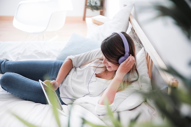 Glückliche hörende Musik der jungen Frau auf dem Bett