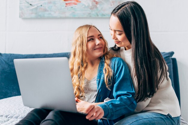 Glückliche homosexuelle Frauen, die Laptop halten