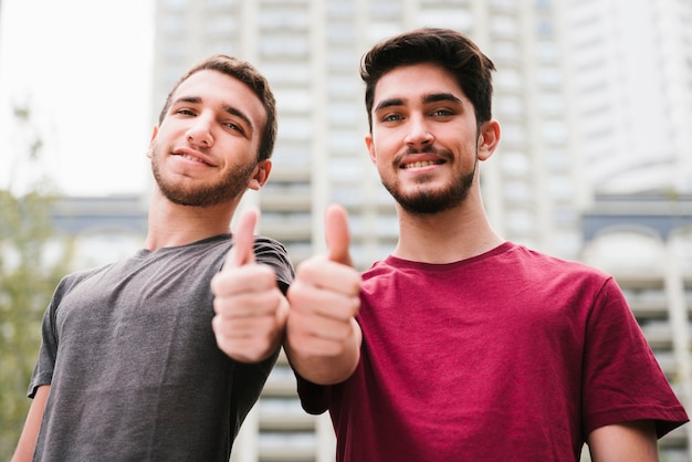 Glückliche homosexuelle Paare mit den Daumen oben