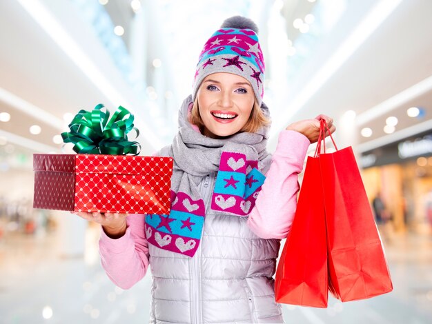 glückliche junge amerikanische Frau mit einem Weihnachtsgeschenk in einer Winteroberbekleidung