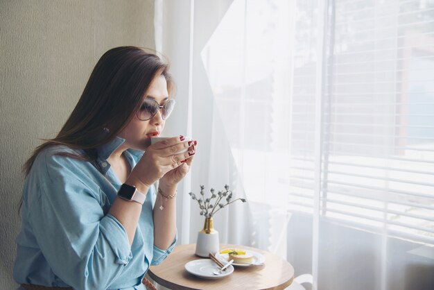 Glückliche junge asiatische Dame des Porträts in der Kaffeestube