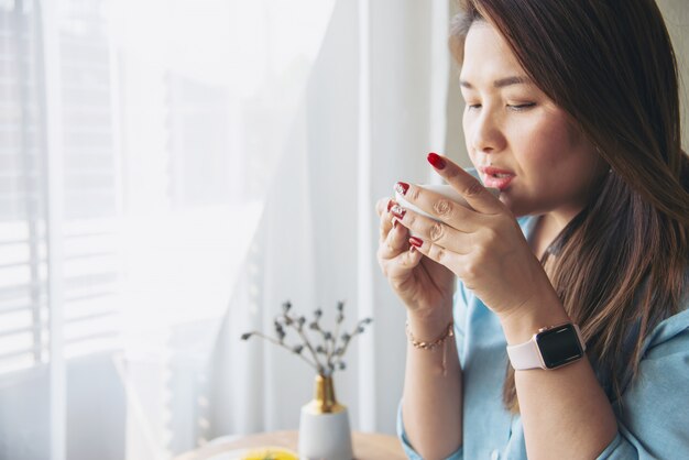 Glückliche junge asiatische Dame des Porträts in der Kaffeestube