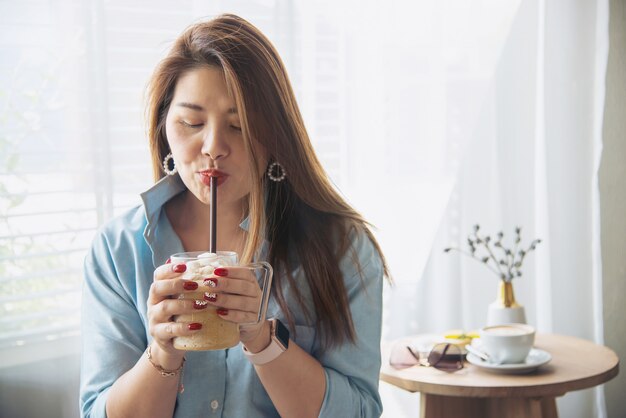 Glückliche junge asiatische Dame des Porträts in der Kaffeestube