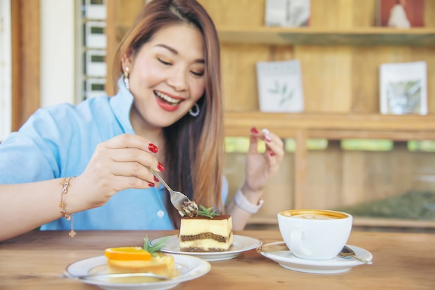 Glückliche junge asiatische Dame des Porträts in der Kaffeestube