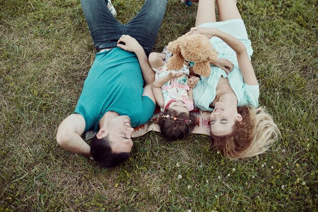 Glückliche junge Familie, die zusammen Zeit draußen in der grünen Natur verbringt.