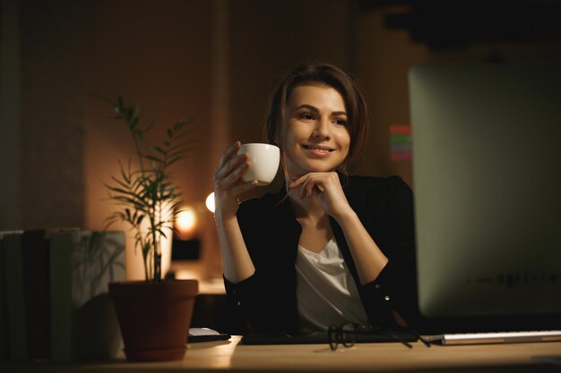 Glückliche junge Frau Designer in der Nacht mit Computer