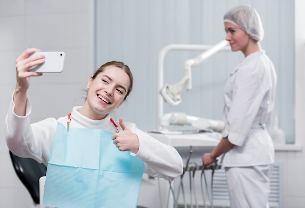 Glückliche junge Frau, die ein selfie am Zahnarzt nimmt
