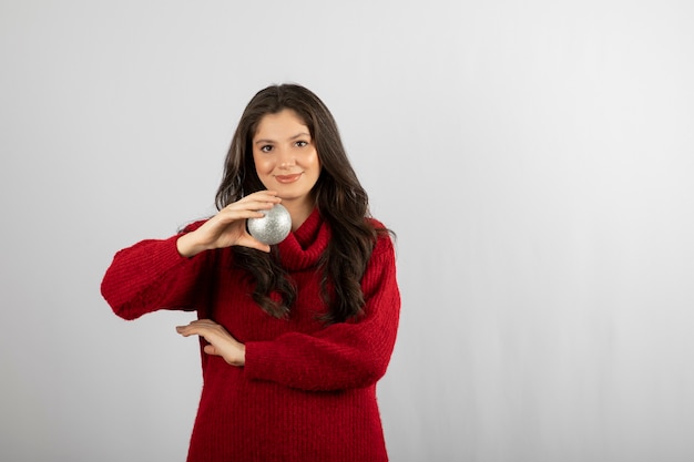 Glückliche junge Frau, die einen Weihnachtsball hält.