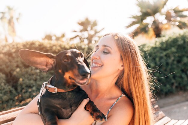 Glückliche junge Frau, die ihren Hund im Park betrachtet