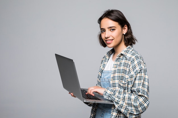 Glückliche junge Frau, die Laptop hält und schaut