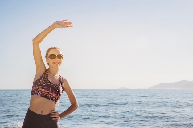 Kostenloses Foto glückliche junge frau, die sich am strand ausdehnt