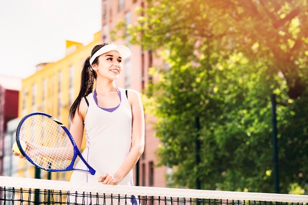 Glückliche junge Frau, die Tennis auf dem Gericht spielt