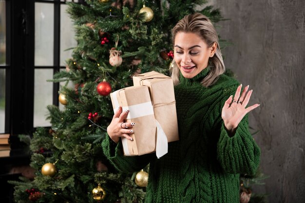 Glückliche junge Frau, die Weihnachtsgeschenkkästen hält