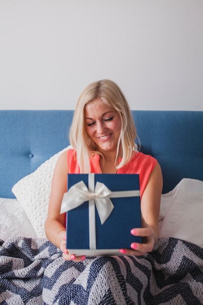 Kostenloses Foto glückliche junge frau hält ein geschenk