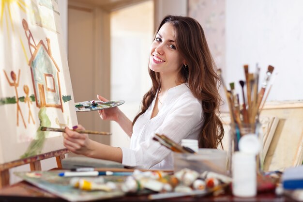 Glückliche junge Frau malt auf Leinwand