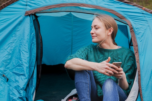 Glückliche junge Frau sitzt in einem Zelt