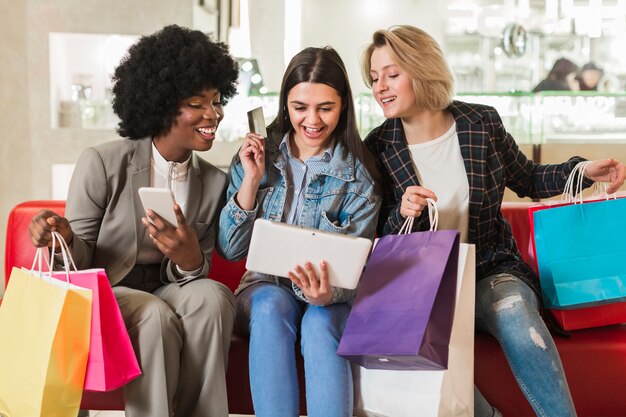 Glückliche junge Frauen, die Einkaufstaschen überprüfen