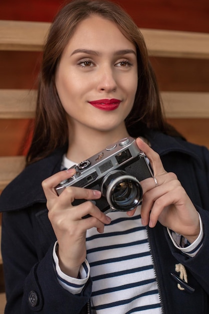 Glückliche junge Hippie-Frau hält Retro-Fotokamera. Spaß in der Stadt mit der Kamera, Reisefoto des Fotografen.