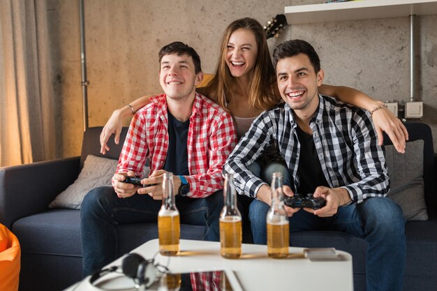 Glückliche junge Leute, die Videospiele spielen, Spaß haben, Freunde zu Hause feiern, Hipster-Gesellschaft zusammen, zwei Männer eine Frau, lächelnd, positiv, entspannt, emotional, lachend, Konkurrenz