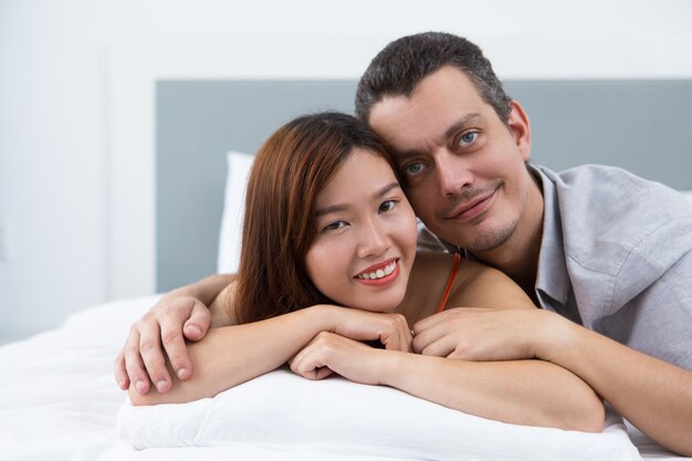 Glückliche junge multiethnische Paar liegt im Bett