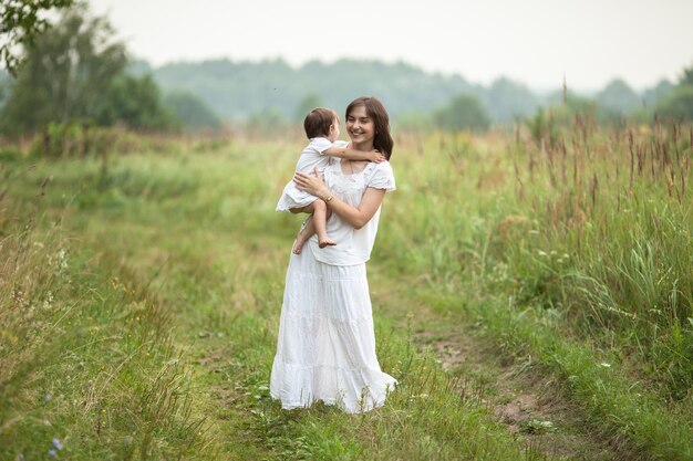 Glückliche junge Mutter mit Kleinkind im Arm zu Fuß