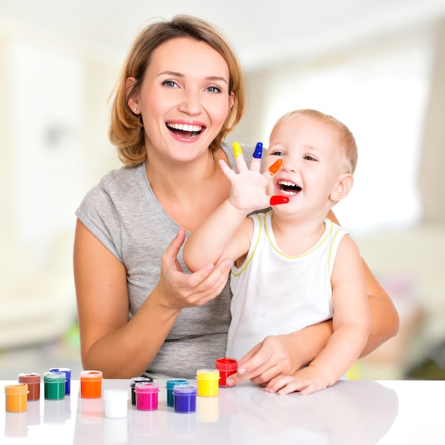 Glückliche junge Mutter und Kind mit gemalten Händen