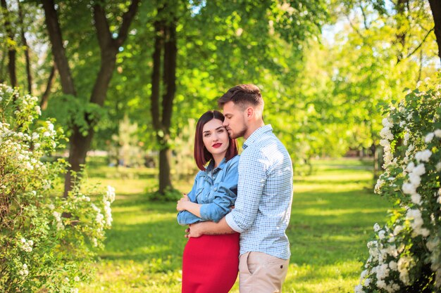Glückliche junge Paare am Park, der am hellen sonnigen Tag steht und lacht