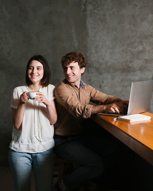 Kostenloses Foto glückliche junge paare, die an laptop arbeiten