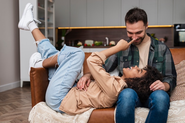 Glückliche junge Paare, die auf Sofa spielen