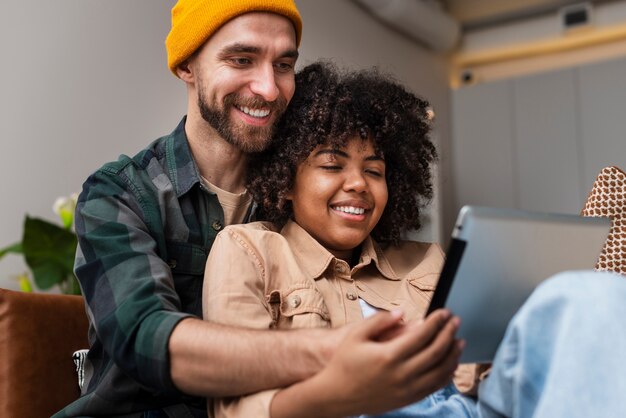 Glückliche junge Paare, die auf Tablette schauen